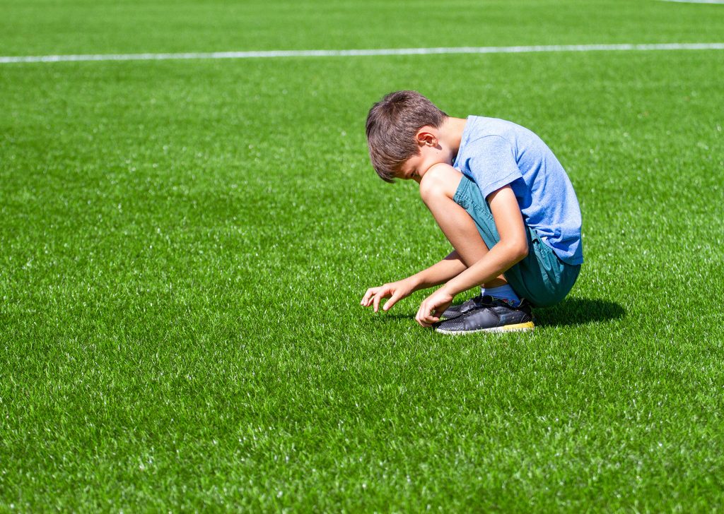 Alone kid sitting on the football field